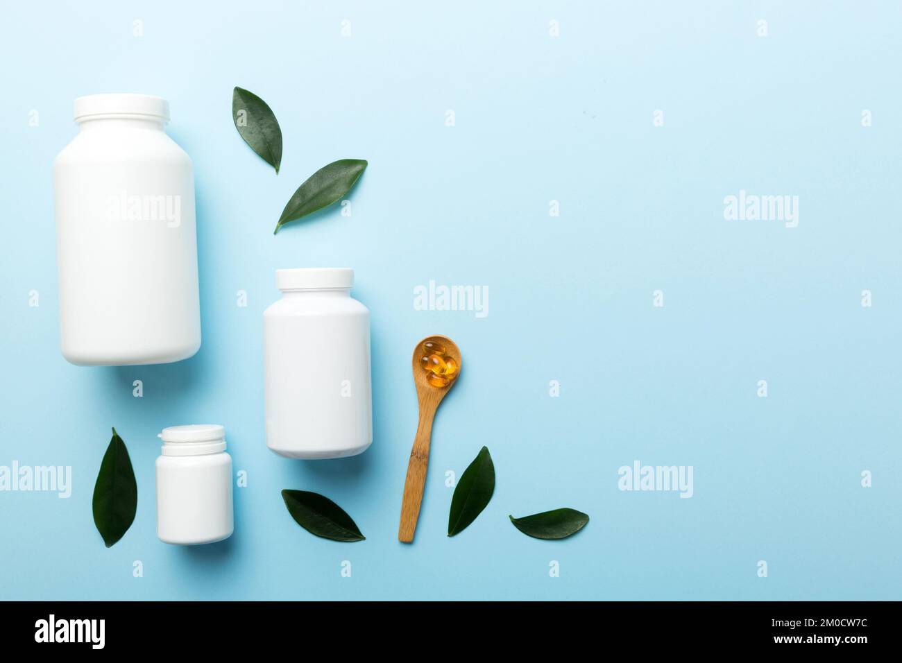 Le capsule di Omega-3 si trovano in un flacone bianco su un tavolo con il fondo verde delle foglie. Compresse di olio di pesce. Additivi biologicamente attivi omega 6, omega 9, vitam Foto Stock