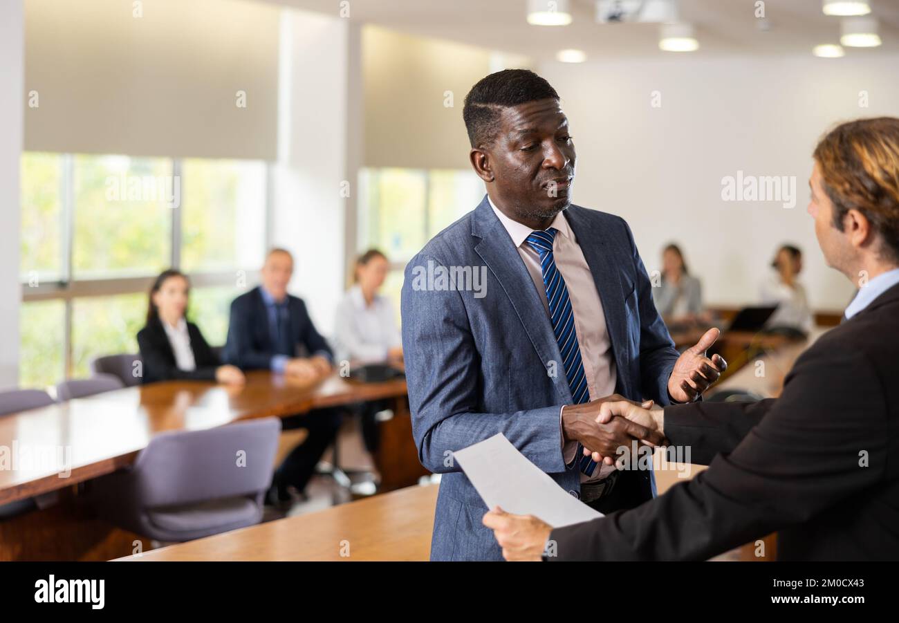 Uomini d'affari positivi handshaking dopo la firma del contratto Foto Stock