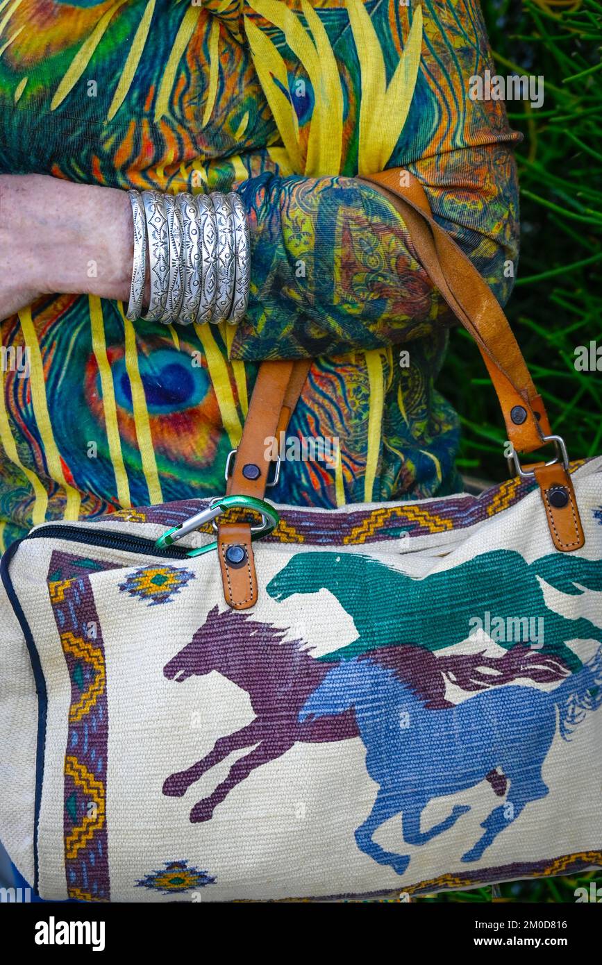Primo piano di una donna vestita con un tessuto tessuto tessuto Southwest borsa di cavalli da corsa con braccialetti argentati native American bracciale Foto Stock