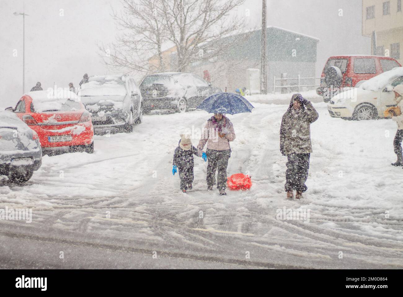 La famiglia cammina per la strada sotto la neve Foto Stock