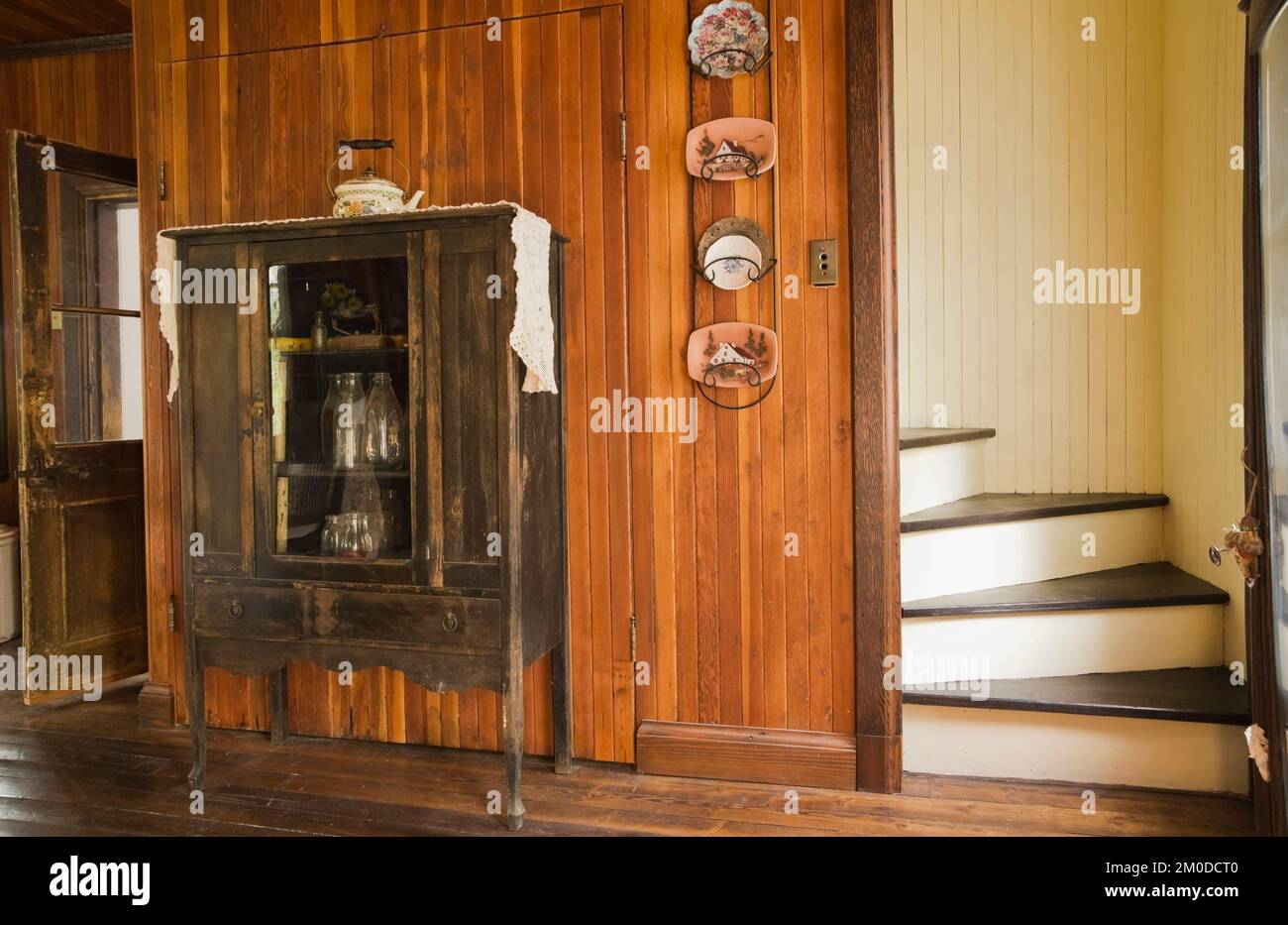 Armadietto antico con vecchie bottiglie di latte in cucina all'interno di una vecchia casa in stile cottage canadese del 1826. Foto Stock