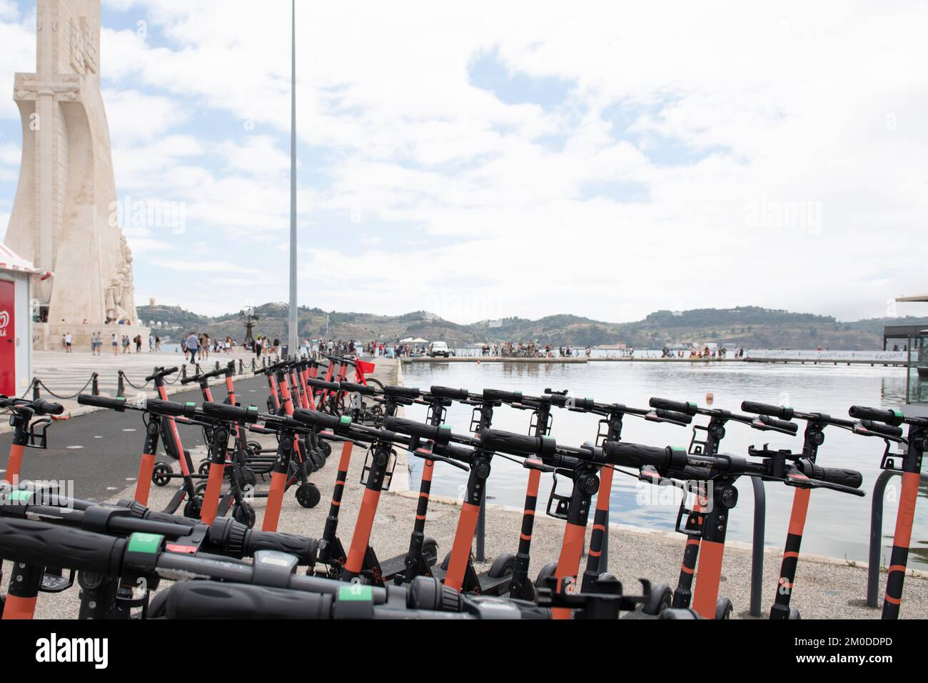 Una spianata vicino al porto di Lisbona piena di turisti e pattini elettrici Foto Stock
