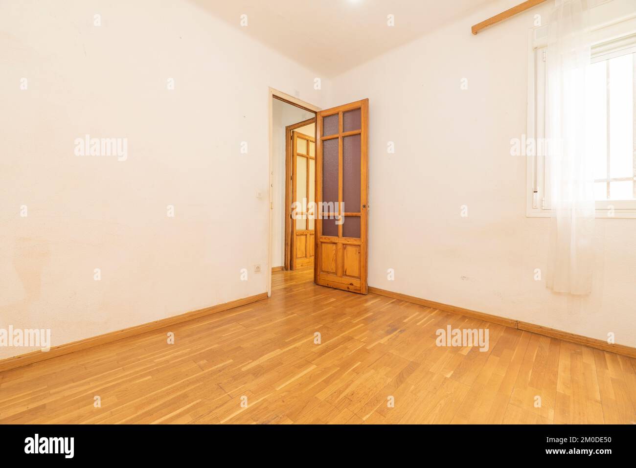 Camera vuota con pavimento in laminato di quercia francese, battiscopa coordinata e porte in legno di pino massiccio con vetro Foto Stock