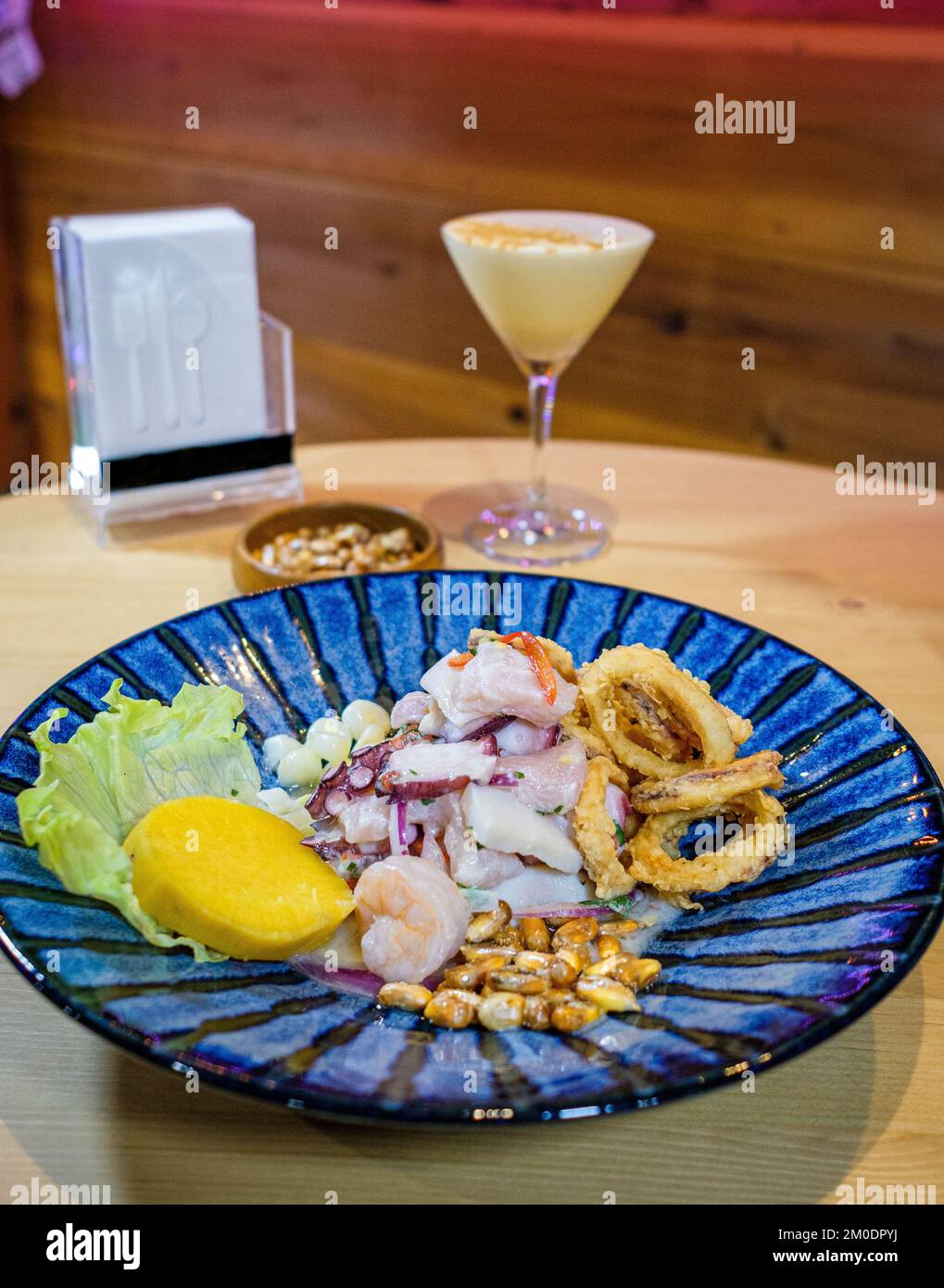 Ceviche peruviane servite su un piatto blu, accompagnato da Pisco e mais tostato Foto Stock