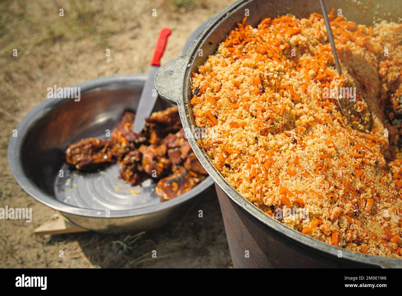 Tradizionale pilaf orientale in grande calderone in una giornata di sole all'aperto. Vero pilaf dell'asia centrale nella steppa Foto Stock
