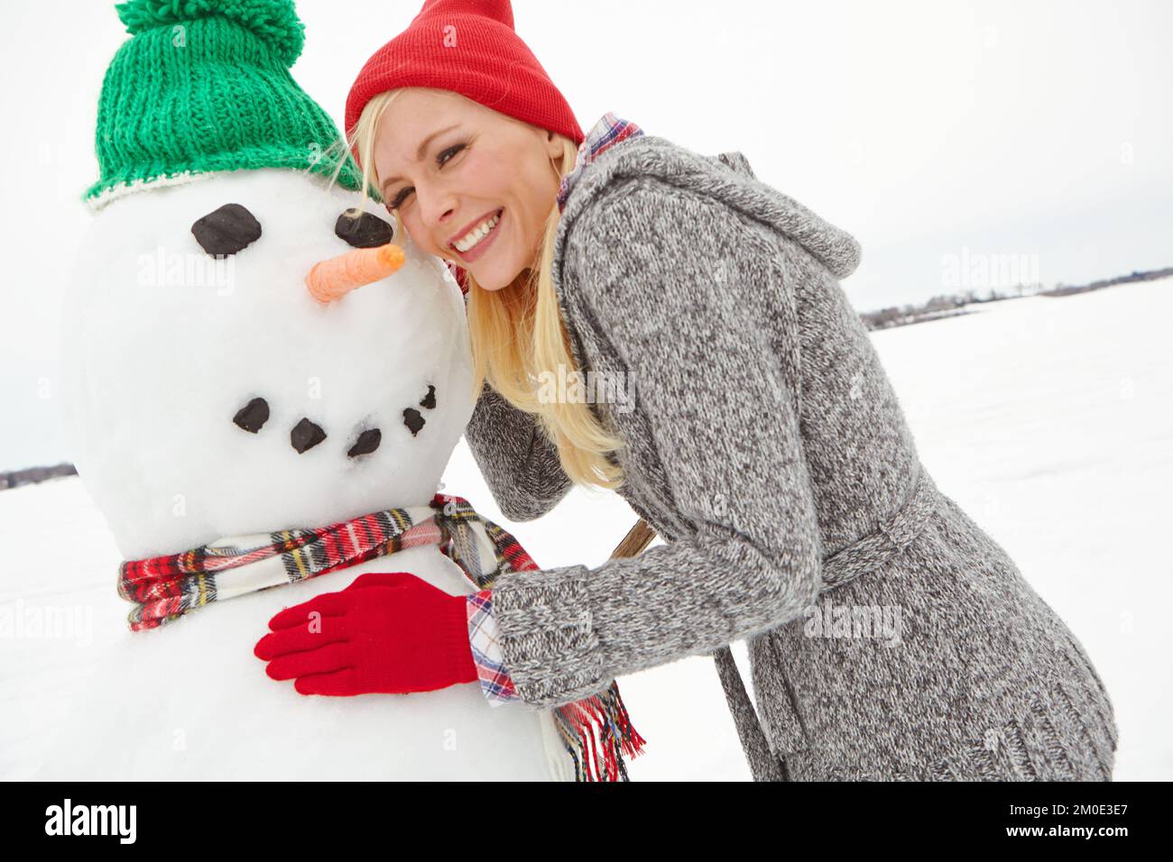 Snowman costruzione, donna e felice ritratto di una persona in vacanza invernale e vacanza per natale. Sorriso, felicità e divertimento nella sensazione di spettacolo Foto Stock