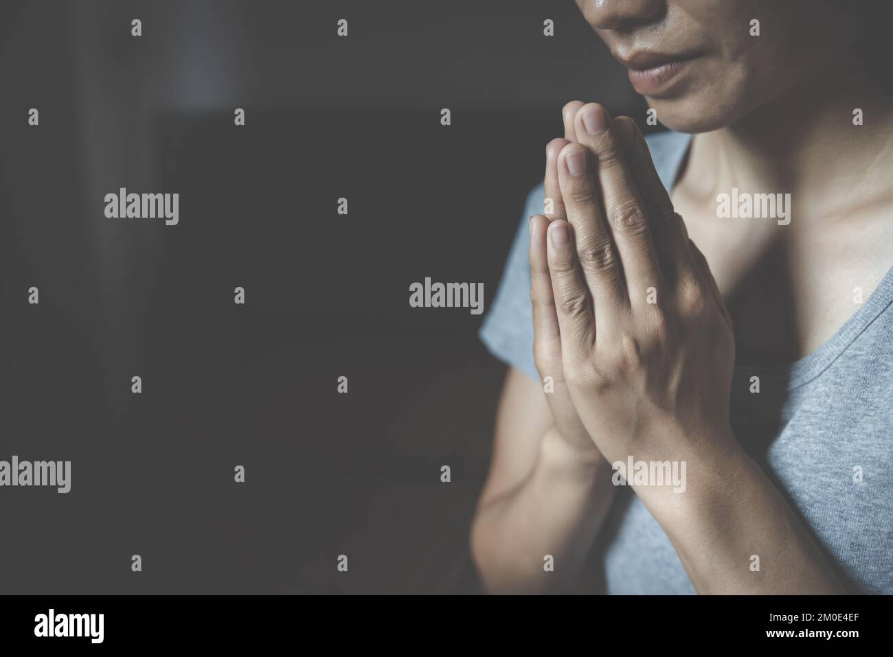 Concetto di preghiera di rispetto di paga per la spiritualità di fede e la religione sfondo grigio. Credenze religiose vita cristiana crisi preghiera a dio. Foto Stock