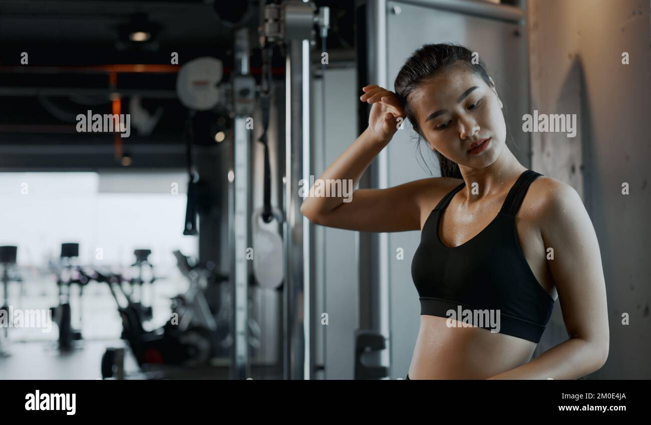 Donna atletica stanca che asciuga il sudore in palestra. Foto Stock