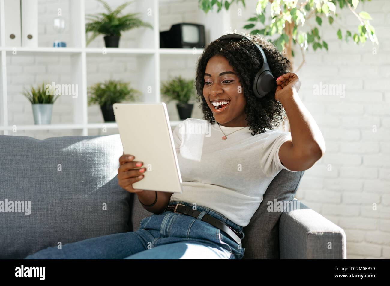 Giovane donna africana che usa un tablet digitale e sorridente mentre si riposa a casa. Foto Stock