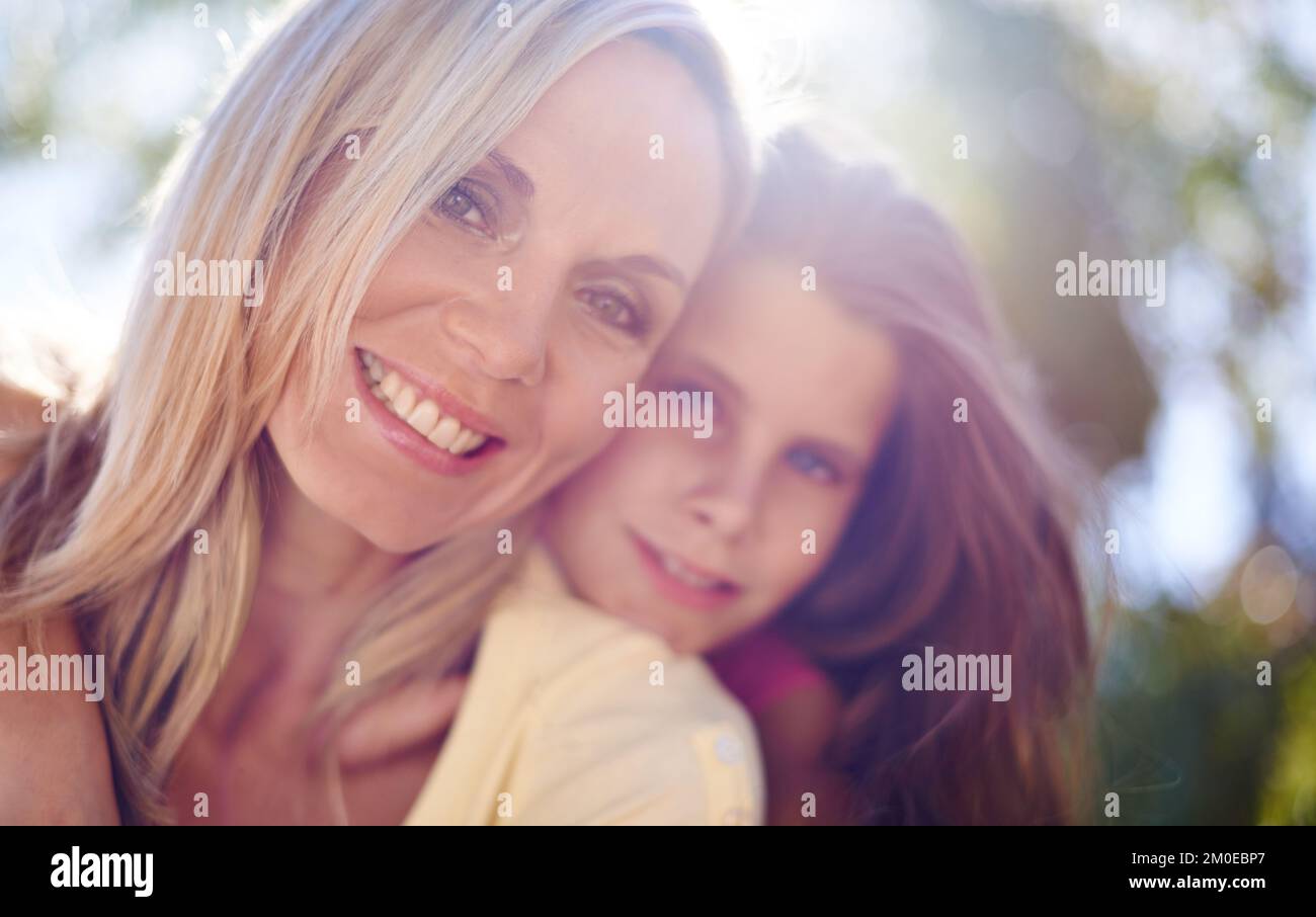 Sia sempre lì per lei. Una madre sorridente con la figlia sulla schiena mentre all'aperto. Foto Stock