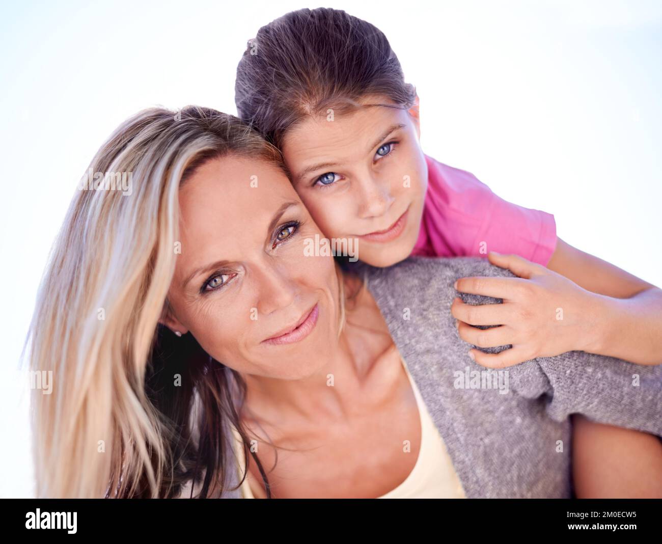 Il loro legame è innegabile. Una madre sorridente con la figlia sulla schiena mentre all'aperto. Foto Stock