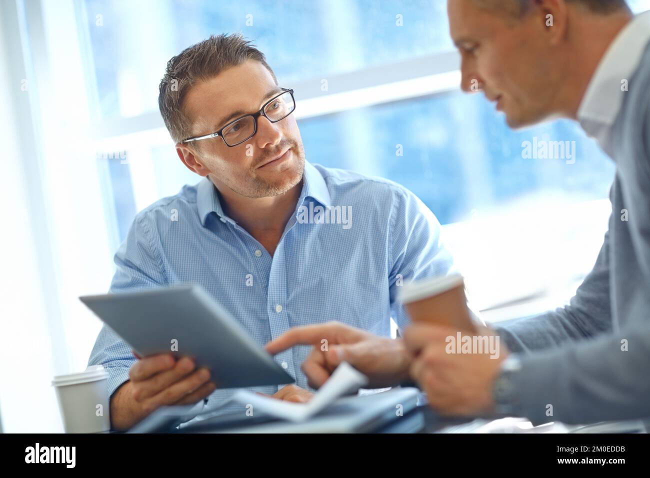 Trovo la vostra proposta intrigante ... uomini d'affari maturi in profonda discussione mentre si utilizza un tablet. Foto Stock