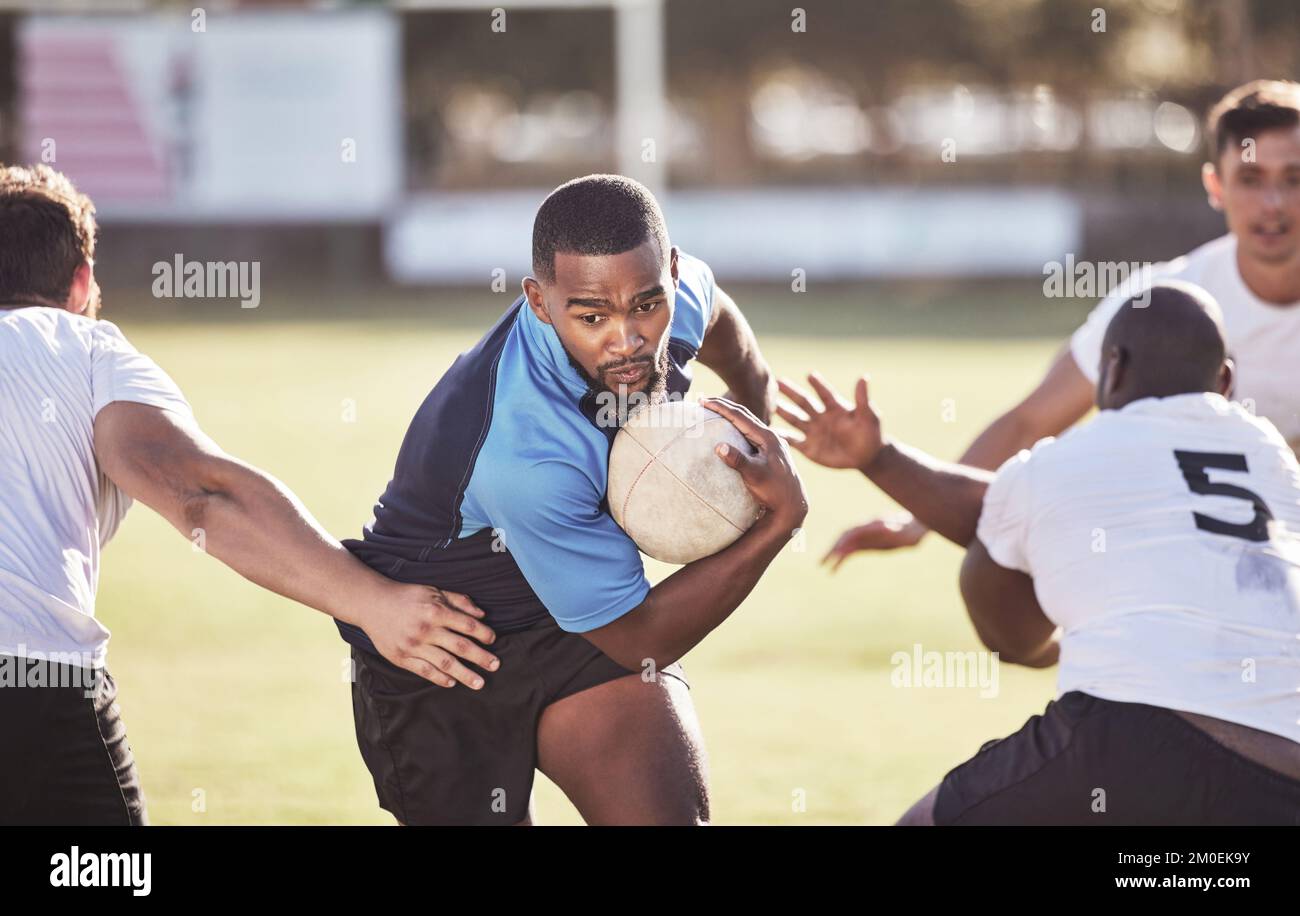 Giocatore di rugby afroamericano che corre via da un avversario mentre tenta di segnare una prova durante una partita di rugby all'esterno su un campo. Uomo nero che fa Foto Stock