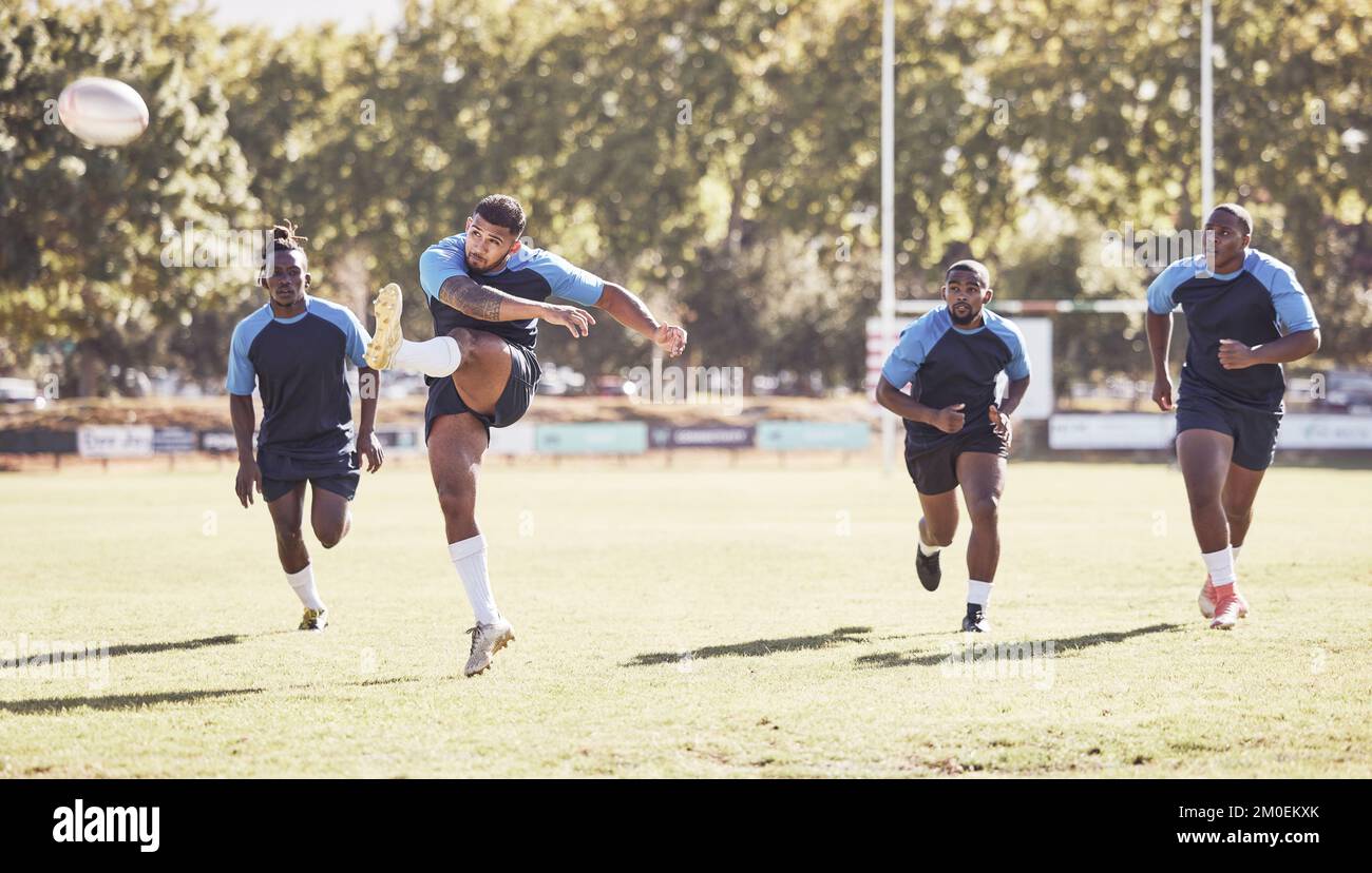 Giocatore di rugby misto che tenta un dropkick durante una partita di rugby fuori sul campo. L'uomo ispanico sta calciando per il tocco o sta tentando di segnare tre Foto Stock