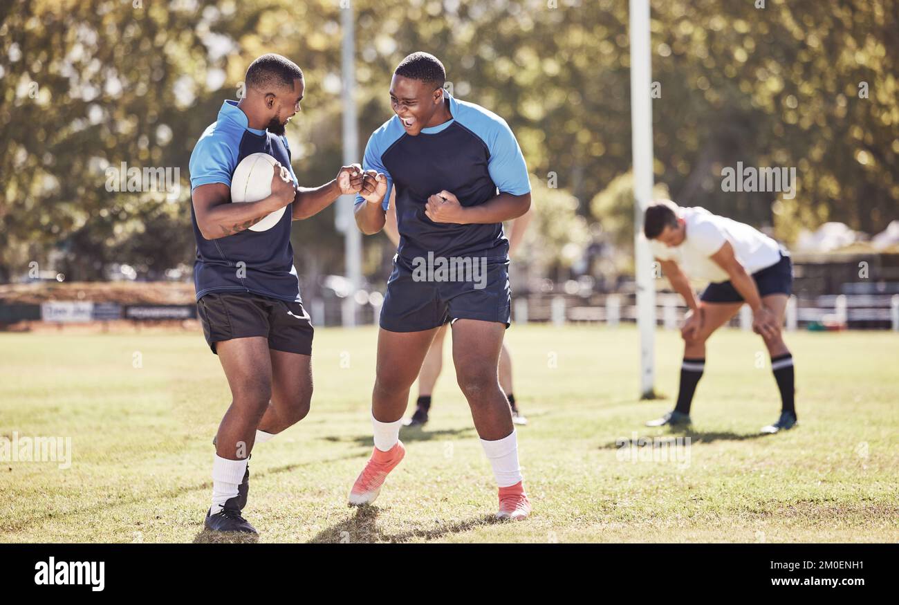 Due compagni di rugby afroamericani festeggiano la possibilità di provare o vincere una partita all'aperto su un campo sportivo. I giocatori di rugby allietano durante una partita Foto Stock