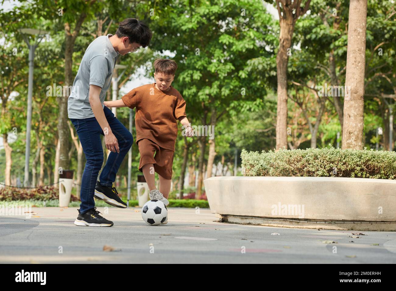 Padre e figlio giocano a calcio nel parco il sabato mattina Foto Stock