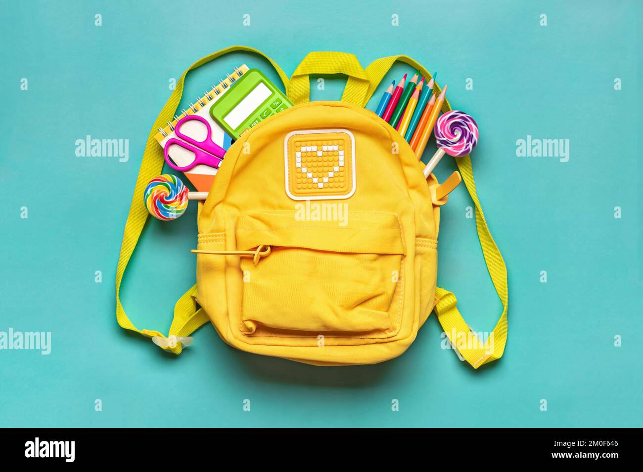 Torna alla scuola, concetto di istruzione zaino giallo con forniture scolastiche - notebook, penne, raser rainbow, numeri isolati su sfondo blu Vista dall'alto Foto Stock
