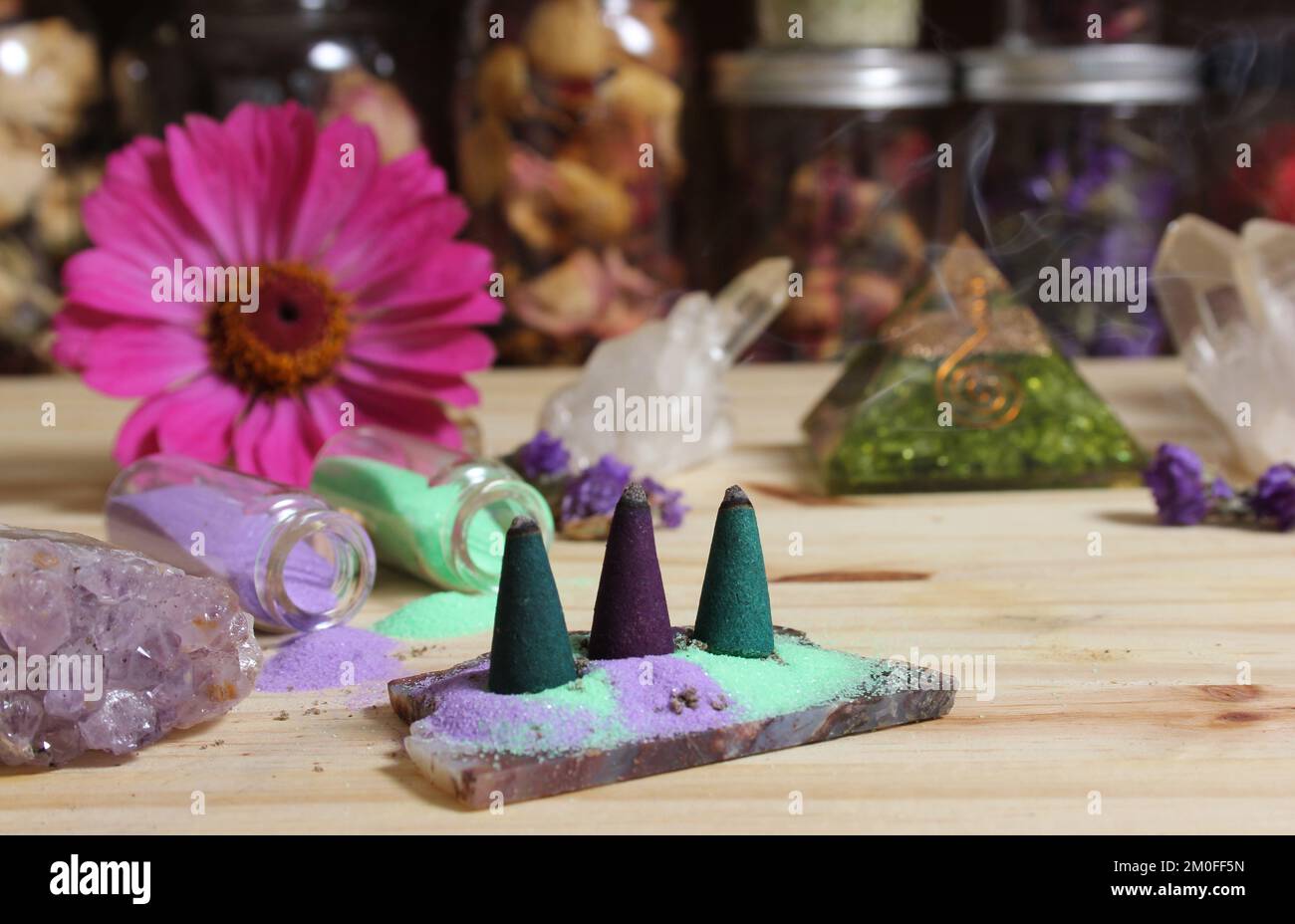Coni di incenso su lastra di pietra con cristalli di Chakra e fiori Foto Stock