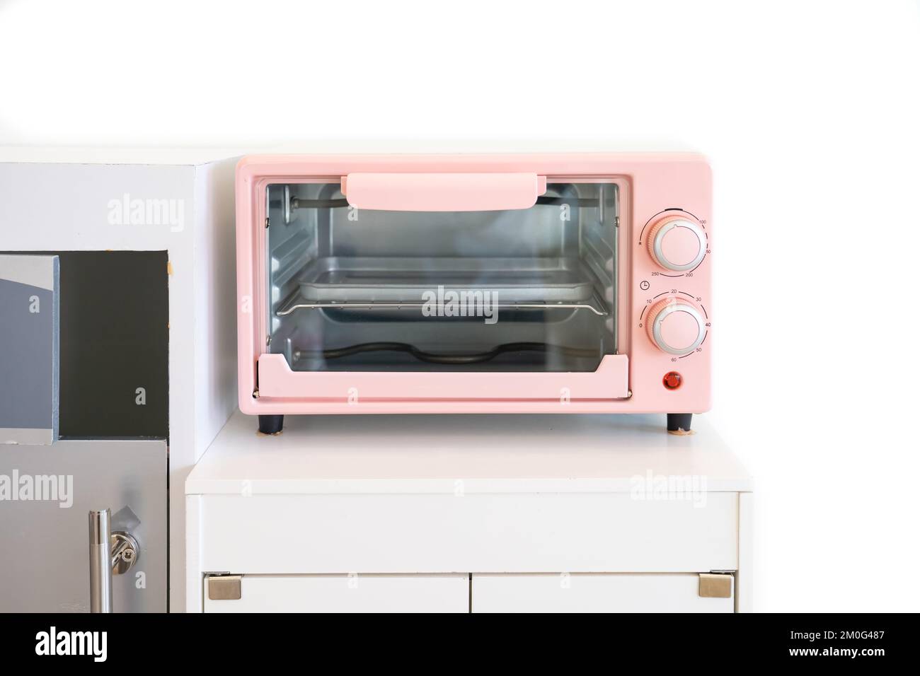 Color pastello rosa del forno a microonde, un moderno apparecchio da cucina  giocattoli per i bambini per preparare un tavolo sistemato in una sala  giochi bianca Foto stock - Alamy