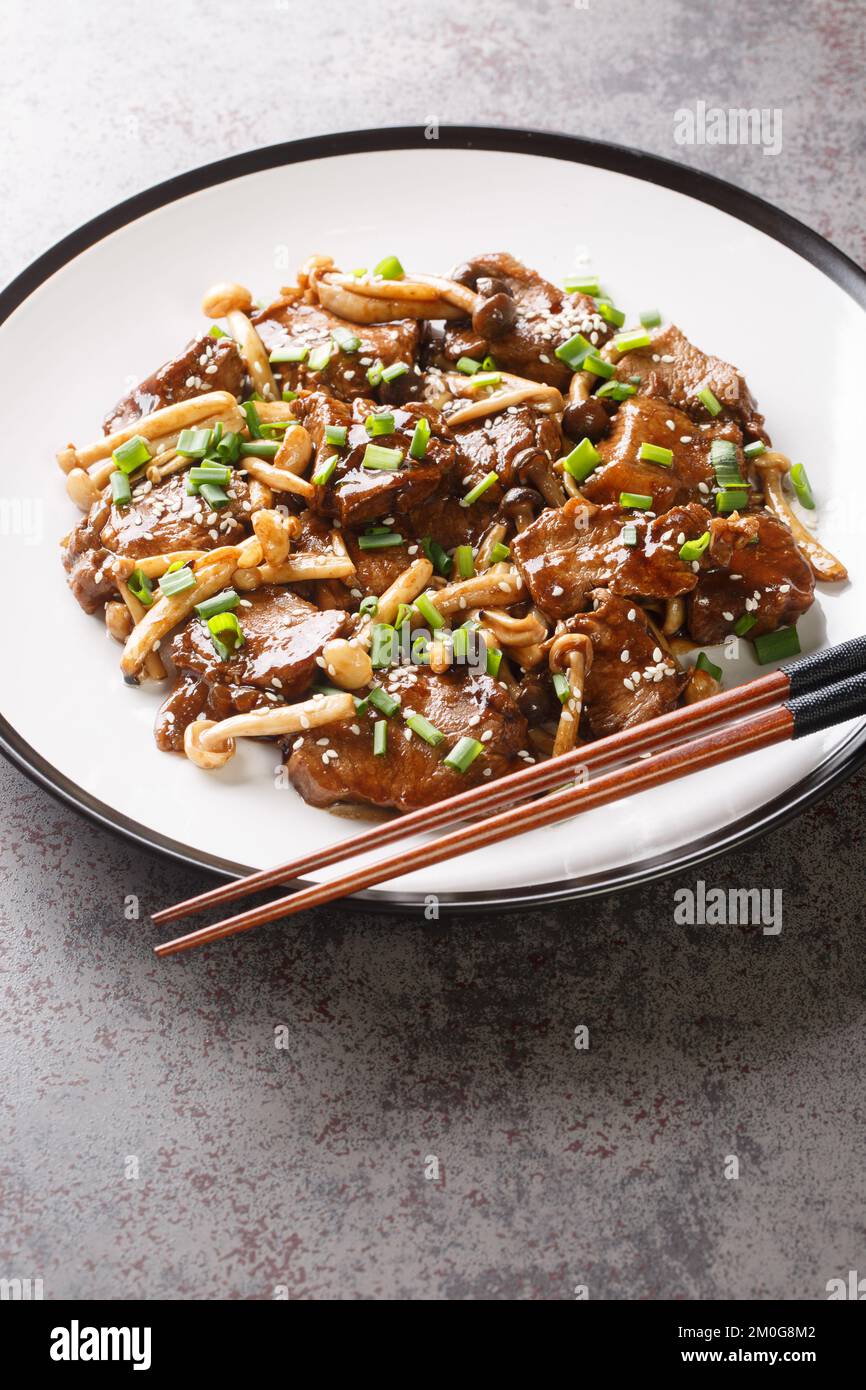 Cibo giapponese speziato teriyaki bistecca di manzo in salsa con funghi primo piano sul piatto sul tavolo. Verticale Foto Stock