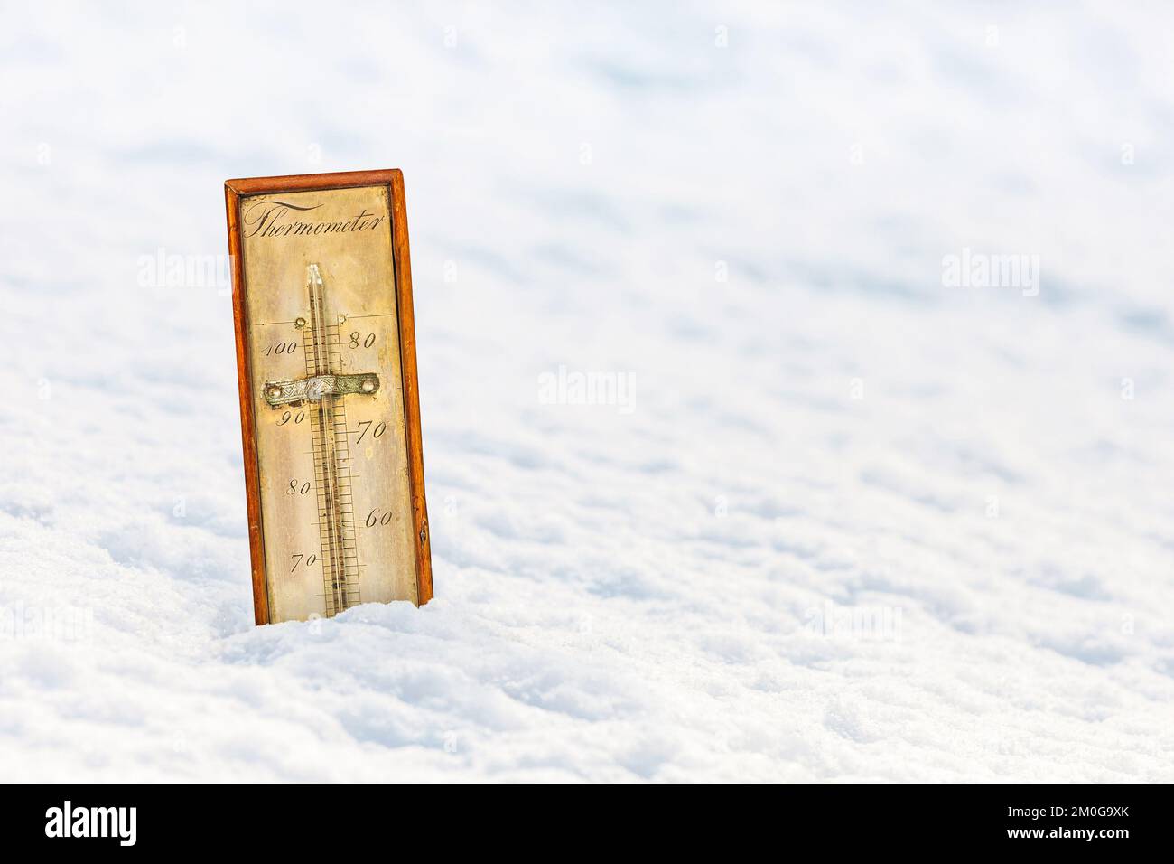 Antico termometro ornamentale in un paesaggio di neve bianca Foto Stock