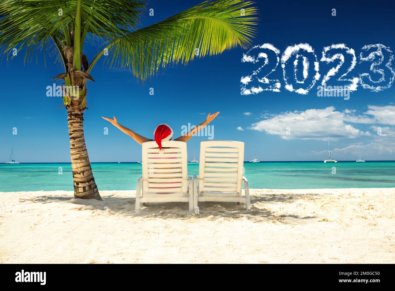 2023 nuovo anno concetto con donna in cappello di babbo natale rilassante sulla spiaggia tropicale. Foto Stock