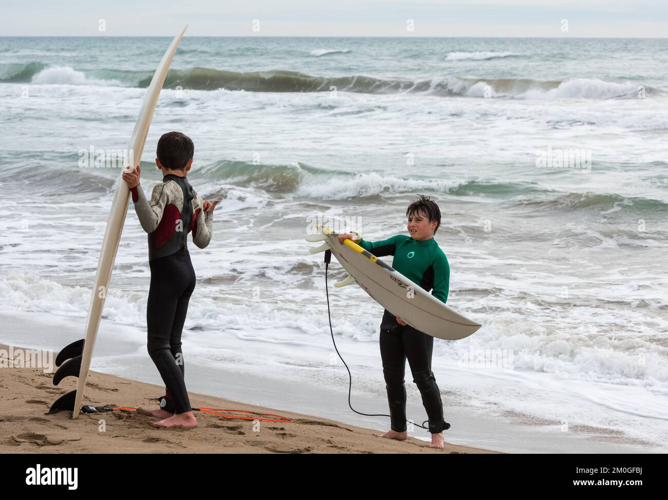 Castelldefels, Barcellona, Spagna - 9 gennaio 2016: Due amici tra i dieci e gli undici anni con le loro tavole da surf godendo di una nuvolosa giornata invernale, re Foto Stock
