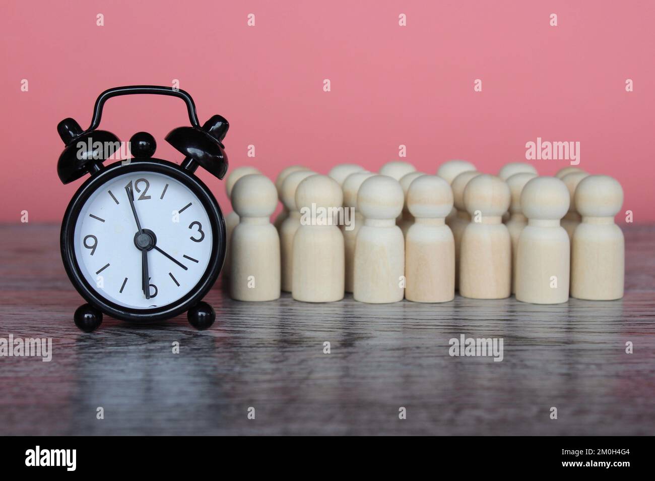 Sveglia e bambole in legno. Gestione del tempo, salari orari, orario di lavoro e tempo di pausa Foto Stock