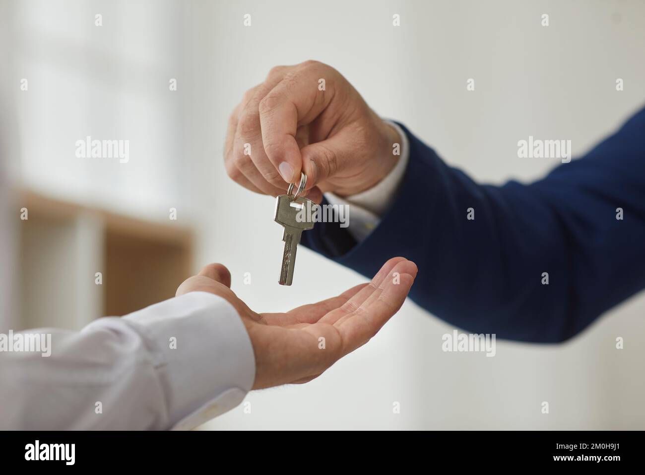 Primo piano irriconoscibile agente immobiliare maschile consegnando la chiave al nuovo proprietario di appartamento. Foto Stock