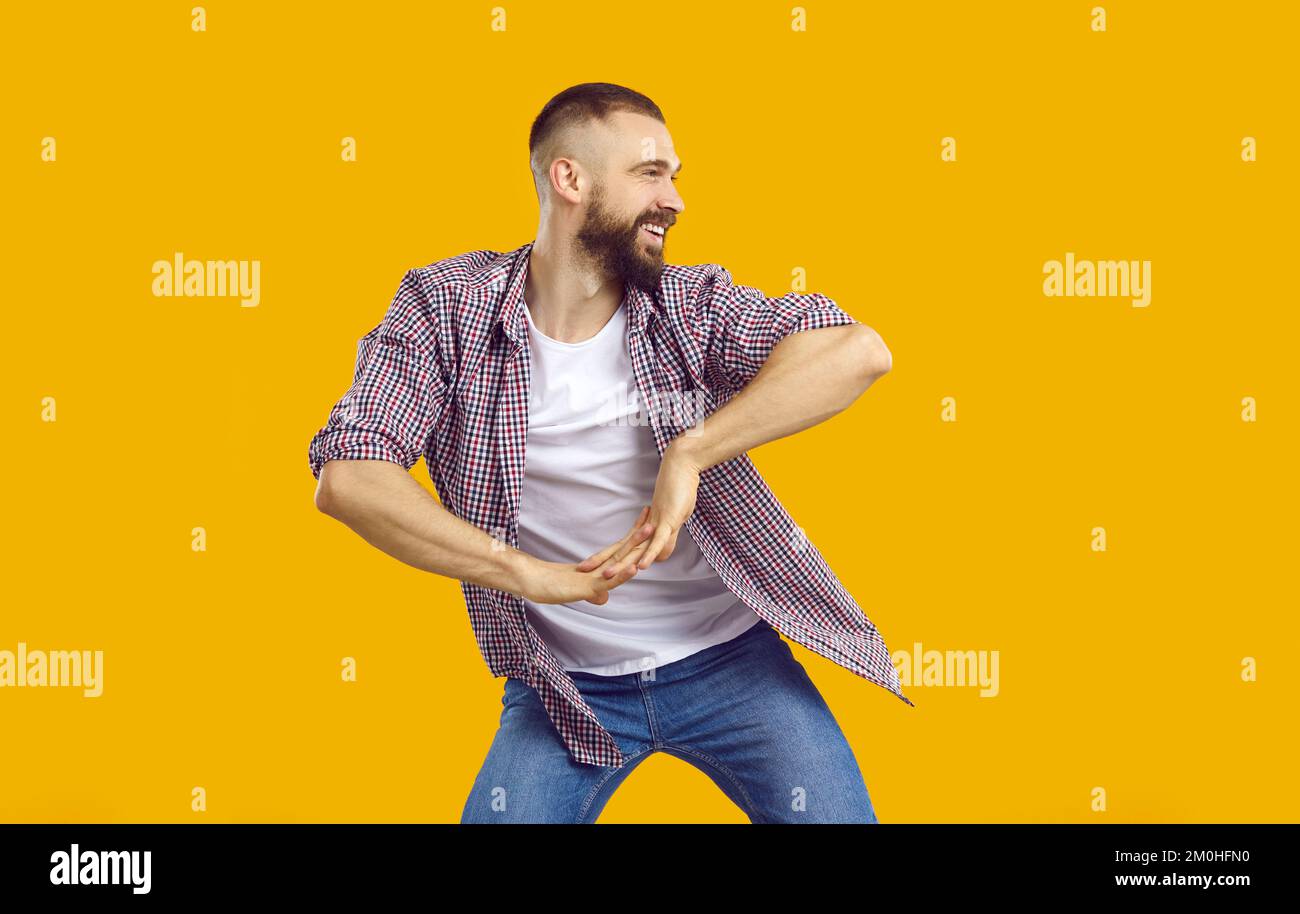 Felice giovane uomo in abiti casual ballando isolato su uno sfondo giallo arancione Foto Stock