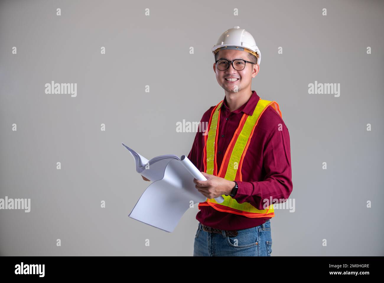 la faccia sorridente dell'ingegnere che tiene un blueprint Foto Stock