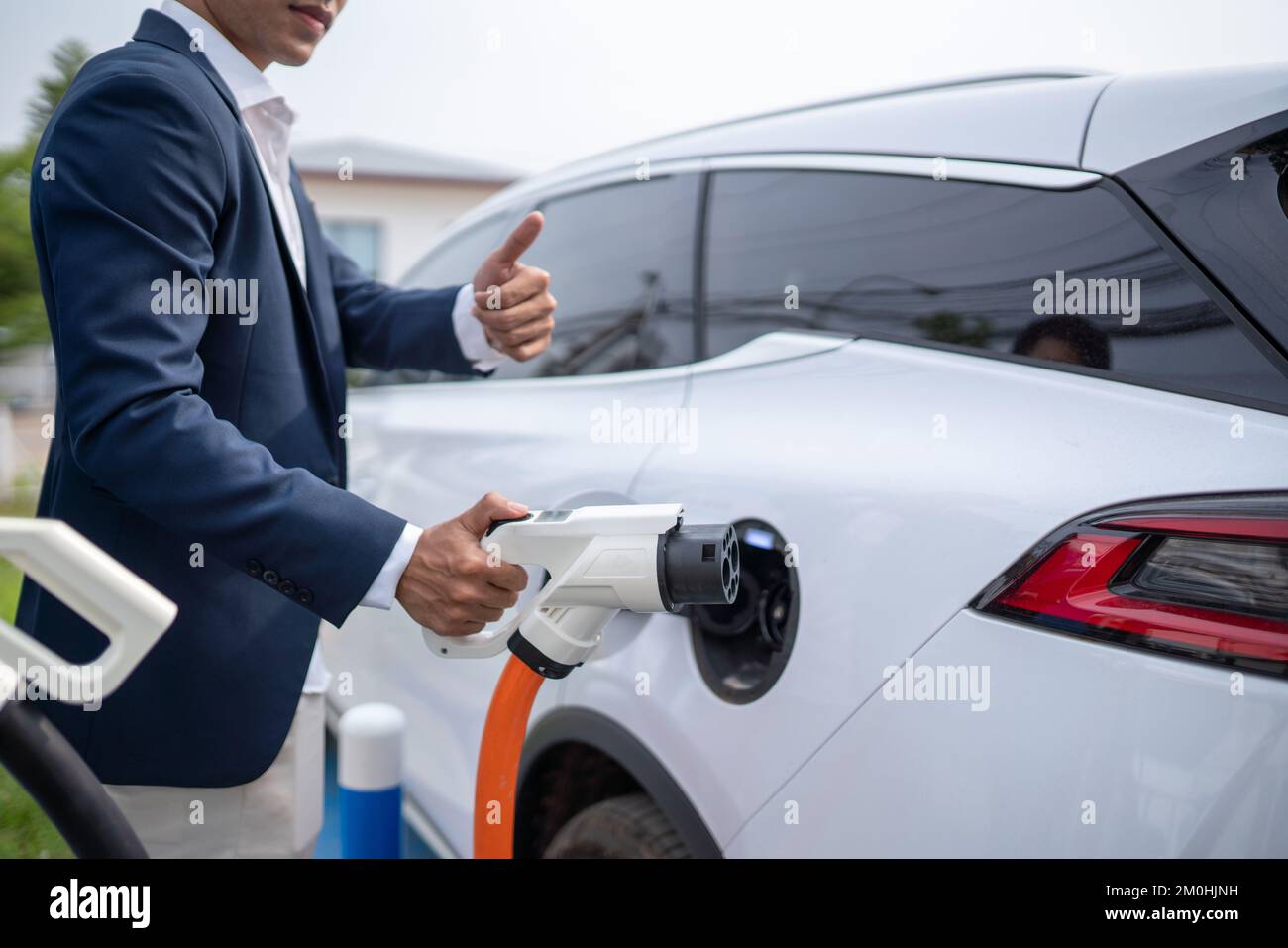 Giovane uomo d'affari che tiene un caricabatterie per veicoli elettrici Foto Stock