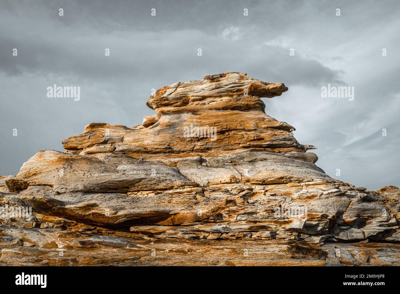 Vista pittoresca di una formazione di pietra naturale contro i cieli cupi. Costa di pietre rosse. Penisola di Sredny, Russia. Foto Stock