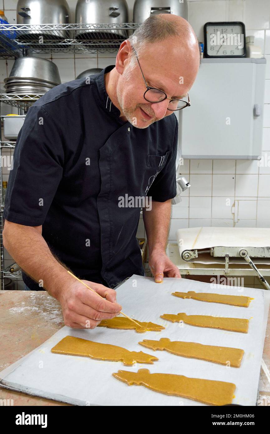 Francia, Meurthe-et-Moselle, Nancy, il pasticciere Didier Hulot fare il pan di zenzero per San Nicola Day, disegno sulla pasta già sagomata Foto Stock