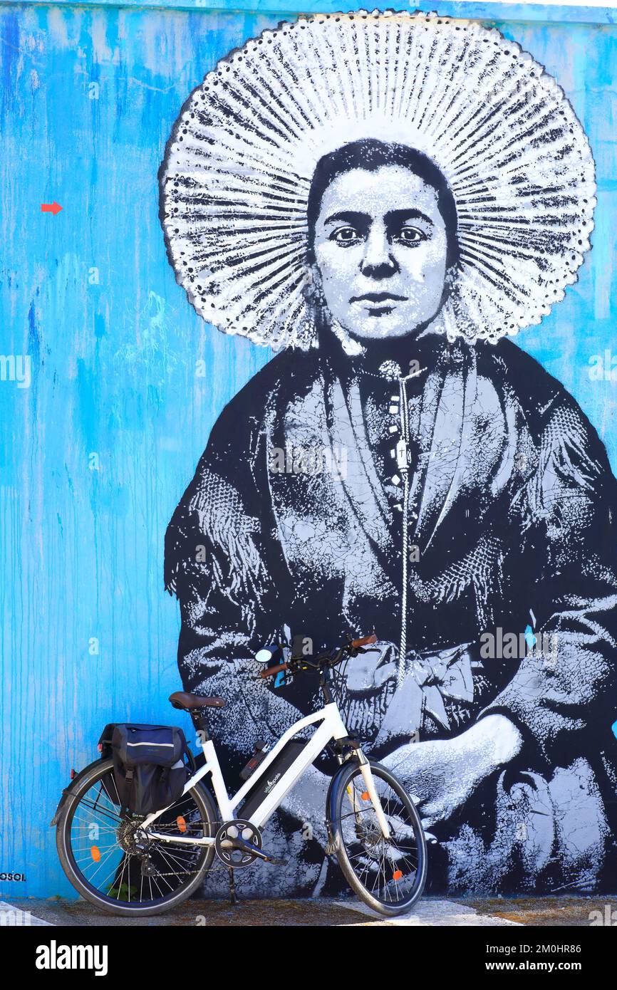 Francia, Pas de Calais, Cote d'Opale (Costa d'Opale), Velomarine, Boulonnais, Deux Baies en Montreuillois, Etaples sur Mer, bici elettrica di fronte a un murale di Jef aerosol raffigurante una donna con un headdress tradizionale della cosiddetta regione del sole Foto Stock