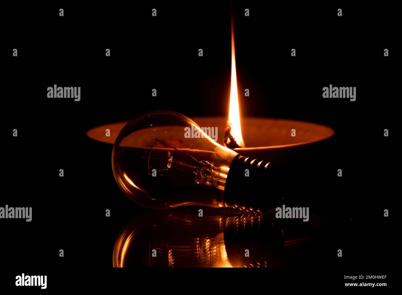 Una corda in olio giace su un piatto e brucia, e accanto ad esso si trova una lampadina sullo specchio al buio, una candela fatta in casa sullo specchio, non c'è alcuna ligh Foto Stock