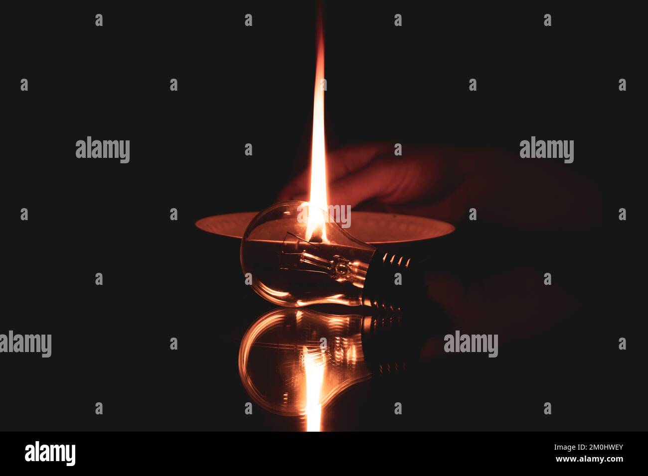 Una corda in olio giace su un piatto e brucia, e accanto ad esso si trova una lampadina sullo specchio al buio, una candela fatta in casa sullo specchio, non c'è alcuna ligh Foto Stock