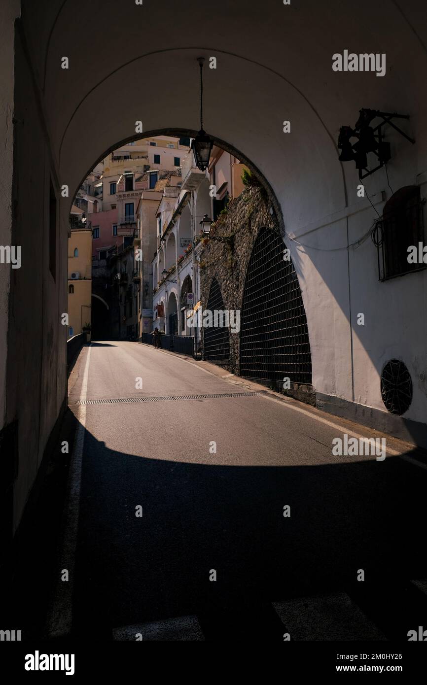Via Matteo Camera tunnel stradale nella città di Amalfi Italia con la luce del sole che splende attraverso l'arco con le case tradizionali alle spalle. Foto Stock