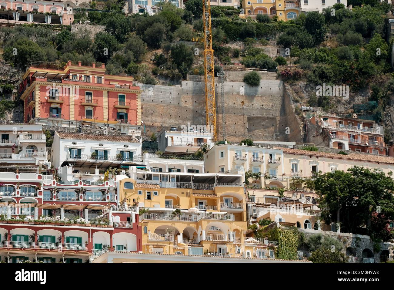 Le case colorate, i negozi e gli alberghi di Positano si stratificano verticalmente sulle scogliere che si affacciano sul porto turistico grande spiaggia Italia. L'immagine mostra la gru in ripresa. Foto Stock