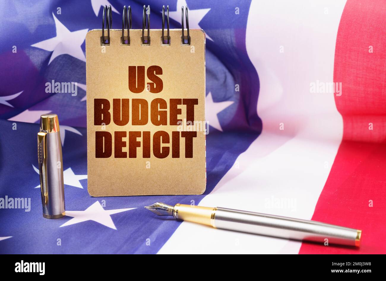 Concetto aziendale. Sullo sfondo della bandiera americana c'è un blocco note con l'iscrizione - il deficit di bilancio degli Stati Uniti Foto Stock