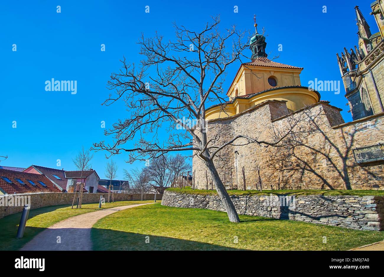 Prato verde di Zahrady na Parkane Giardino di fronte al bastione di pietra e la cupola della scuola parrocchiale della Chiesa di San Bartolomeo, Kolin, Repubblica Ceca Foto Stock