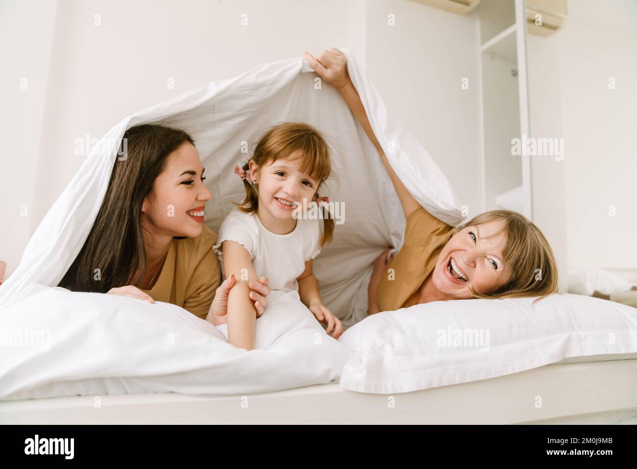 Ragazza bianca che gioca con la madre e la nipote a letto a casa Foto stock  - Alamy