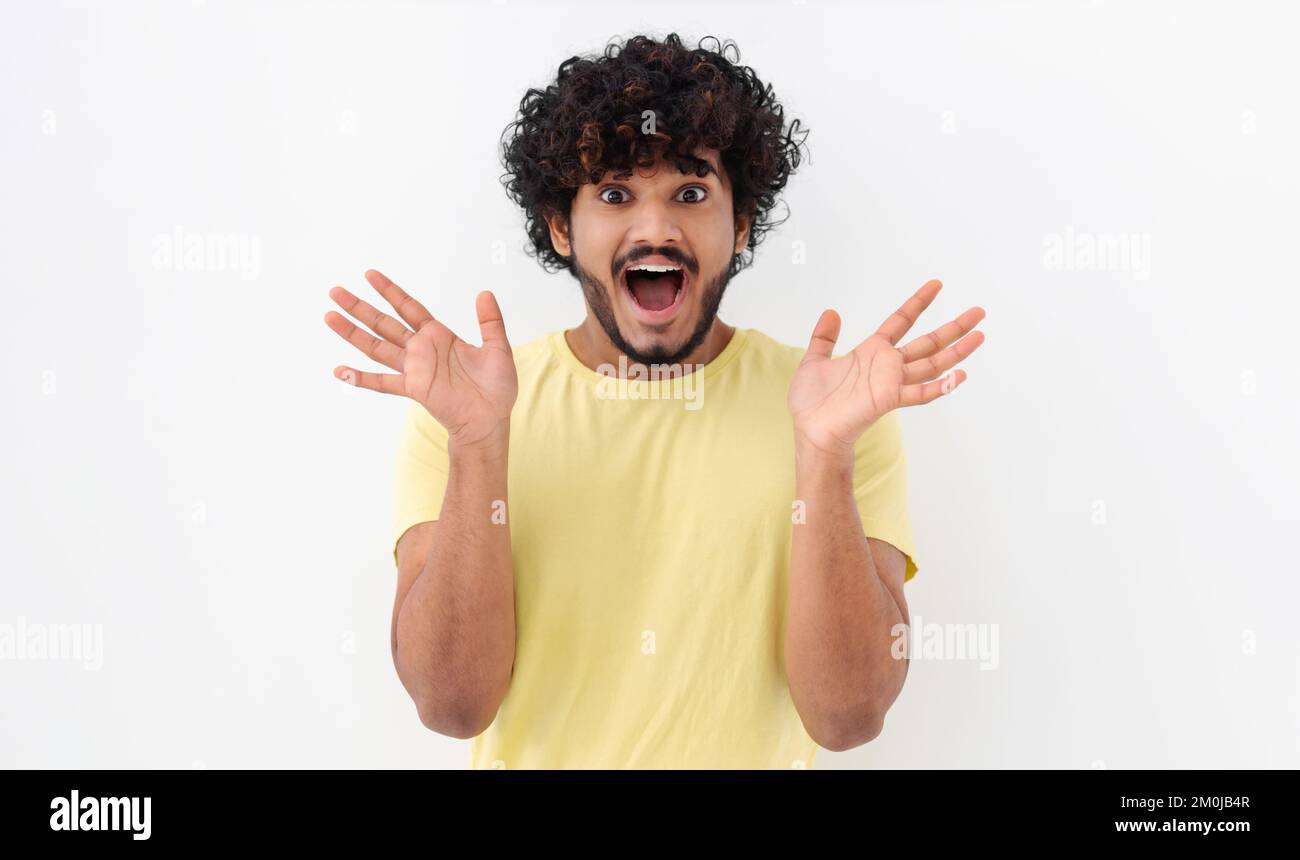Giovane indiano eccitato con i capelli ricci hanno buon umore ritenere emozione eccitato felice su uno sfondo bianco Foto Stock