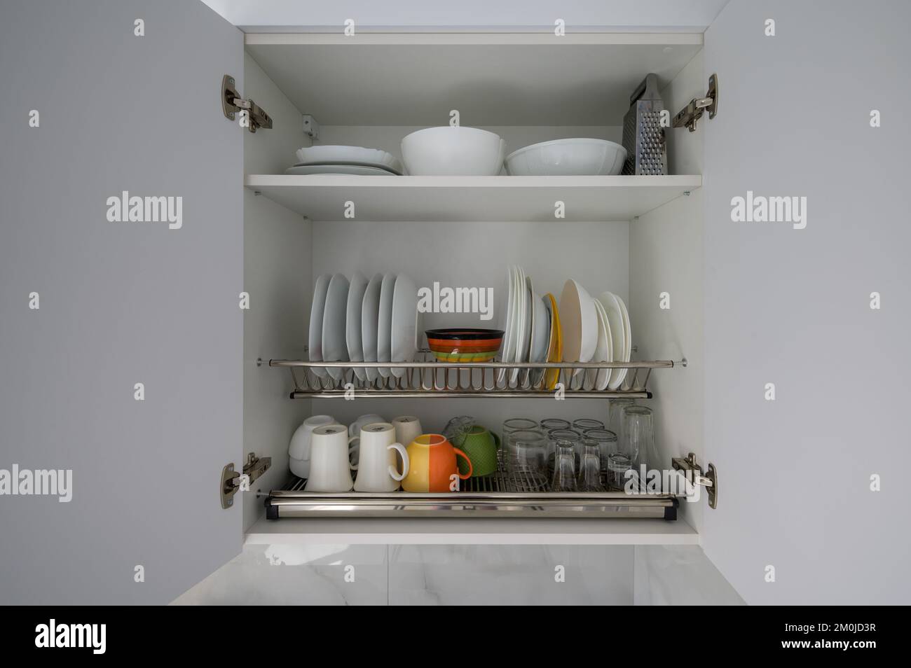 Ampio armadio da cucina bianco aperto con piatti, ciotole, tazze e  bicchieri Foto stock - Alamy