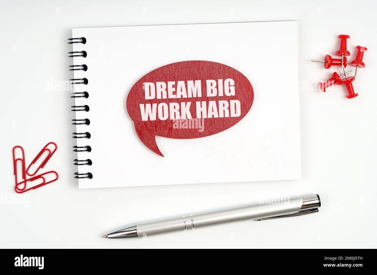 Concetto aziendale. Sul tavolo ci sono cancelleria, un notebook e un segno rosso con l'iscrizione - Dream Big Work Hard Foto Stock