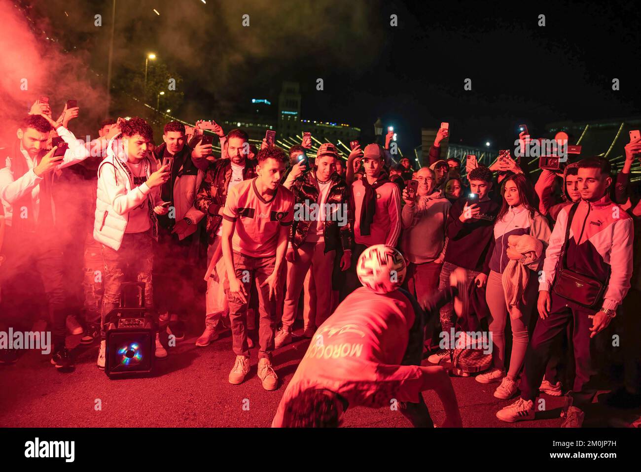 Un uomo marocchino tiene una palla a Las Ramblas, mentre altri scattano foto e lo filmano durante la celebrazione dell'eliminazione della Spagna dalla Coppa del mondo in Qatar. Foto Stock