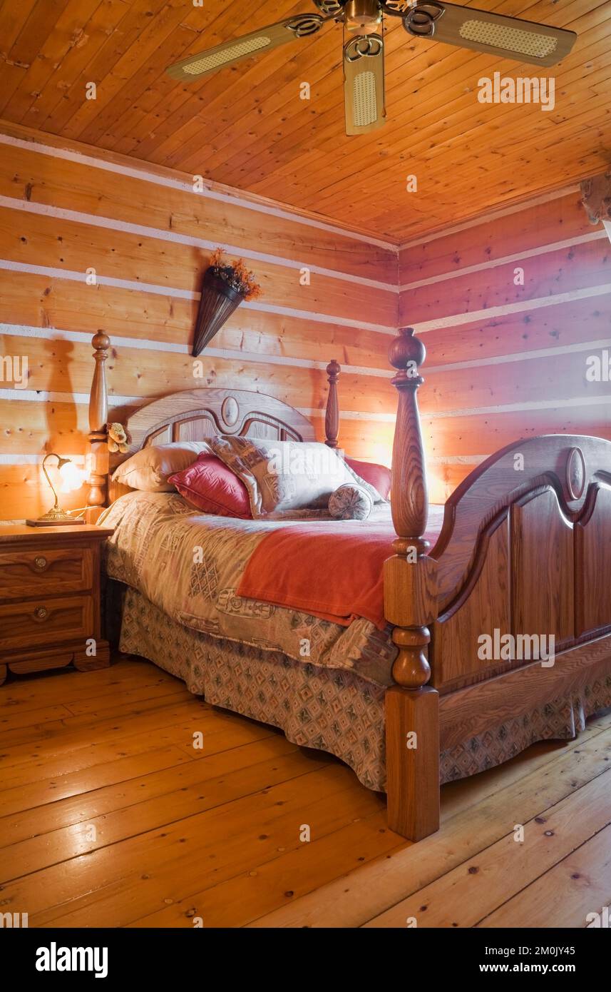 Antico letto a baldacchino in legno e tavolo da notte in camera da letto all'interno 1978 costruito replica della vecchia casa in tronchi 1800s. Foto Stock