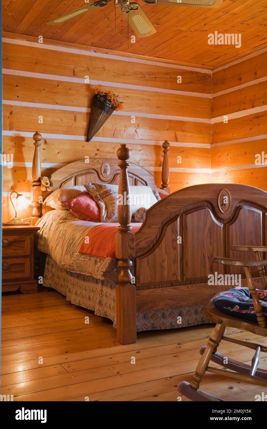Antico letto a baldacchino in legno e tavolo da notte in camera da letto all'interno 1978 costruito replica della vecchia casa in tronchi 1800s. Foto Stock