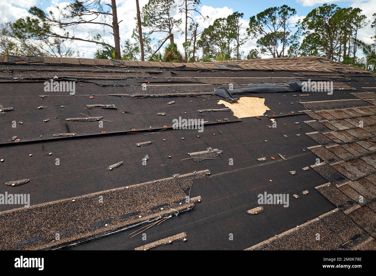 Vento danneggiato tetto casa con scandole di asfalto mancanti dopo l'uragano Ian in Florida. Riparazione del concetto di casa sul tetto Foto Stock