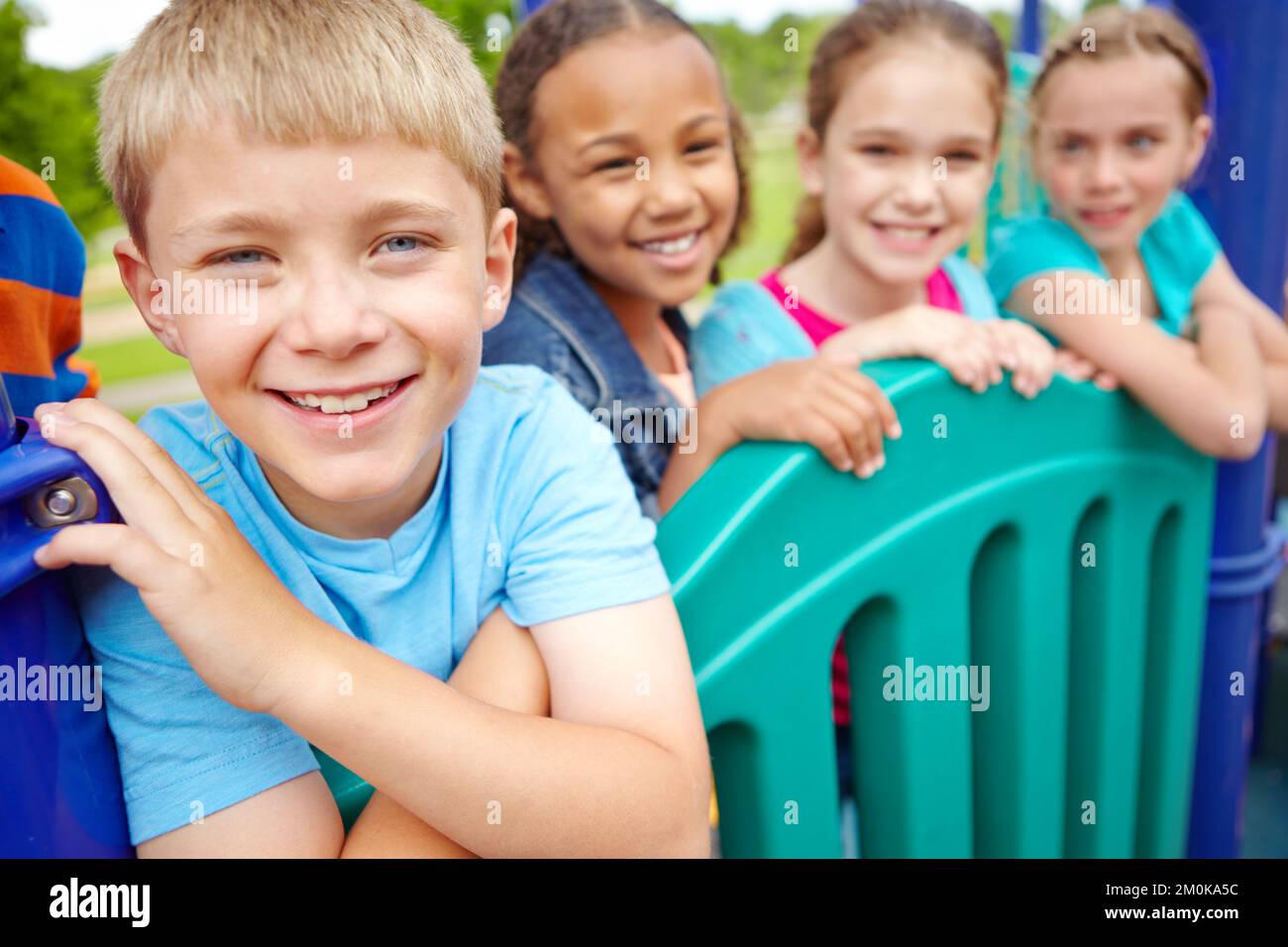 Godendo del tempo trascorso con i suoi amici. Un gruppo multietnico di bambini felici che giocano in una palestra nella giungla in un parco giochi. Foto Stock